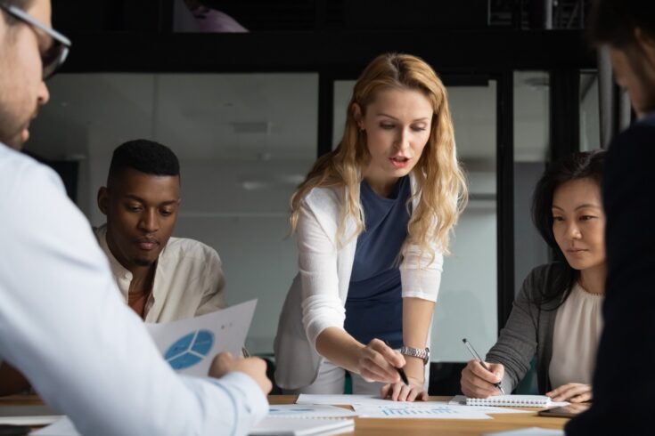 Young businesswoman explaining research results in graphs to colleagues